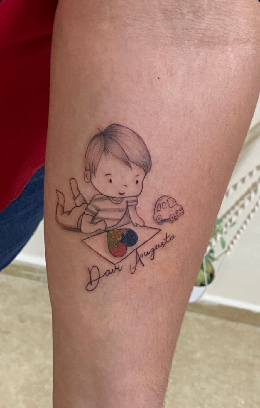 Tattoo delicada de menino brincando com nome em manuscrito