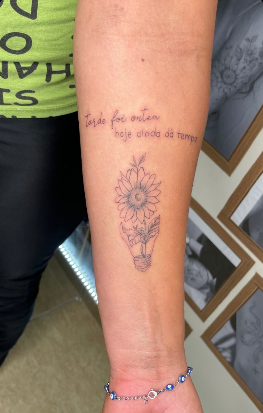 Tattoo floral de girassol em lâmpada com frase manuscrita